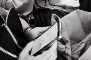Dos personas leyendo en distintos formatos: una frente al teléfono móvil, otra en papel